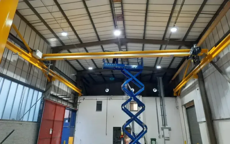Overhead crane system undergoing installation, engineer standing on a MEWP